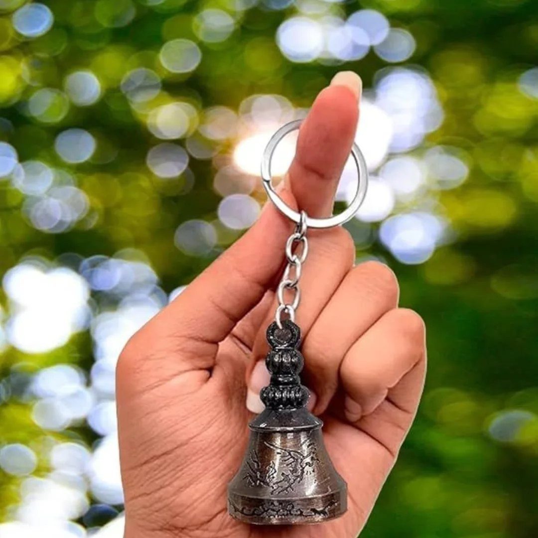 22 Gift Ideas for Brother, From Hoodies to Gadgets 22 Ornate silver bell keychain held in a hand against a blurred green background