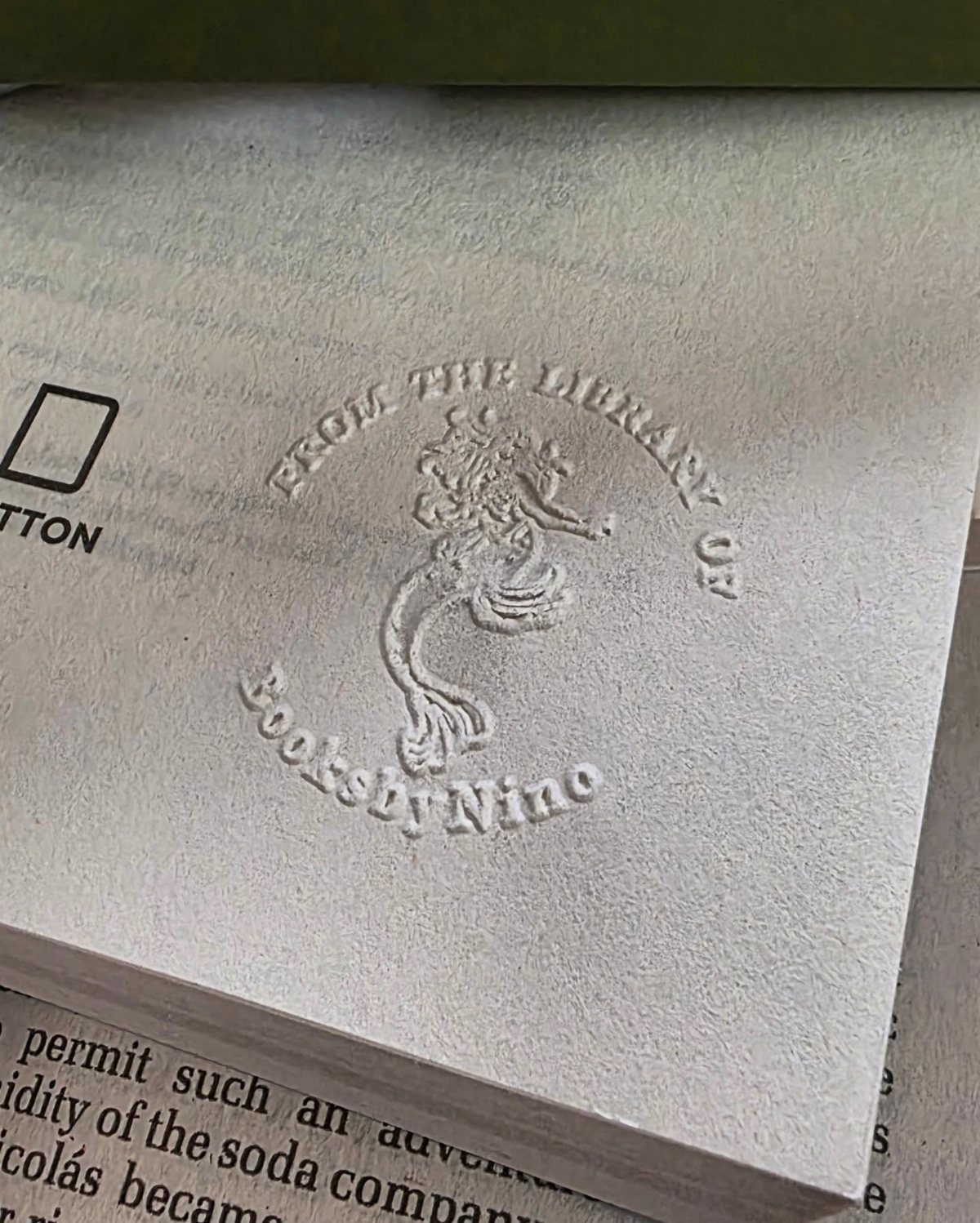 Embossed library seal on a white book page with a mythical creature design.