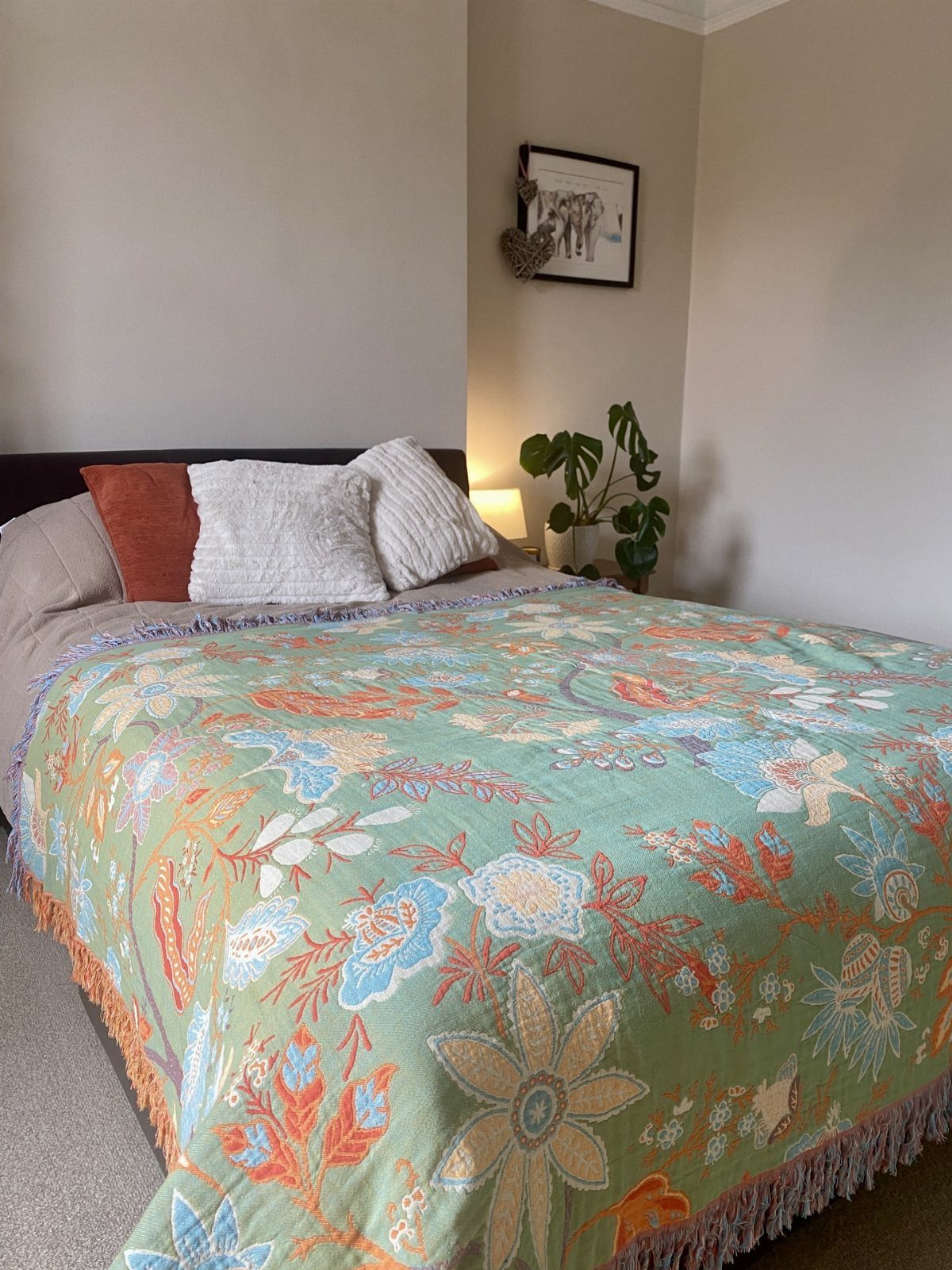 Floral patterned quilt in green and orange on a bed in a bedroom