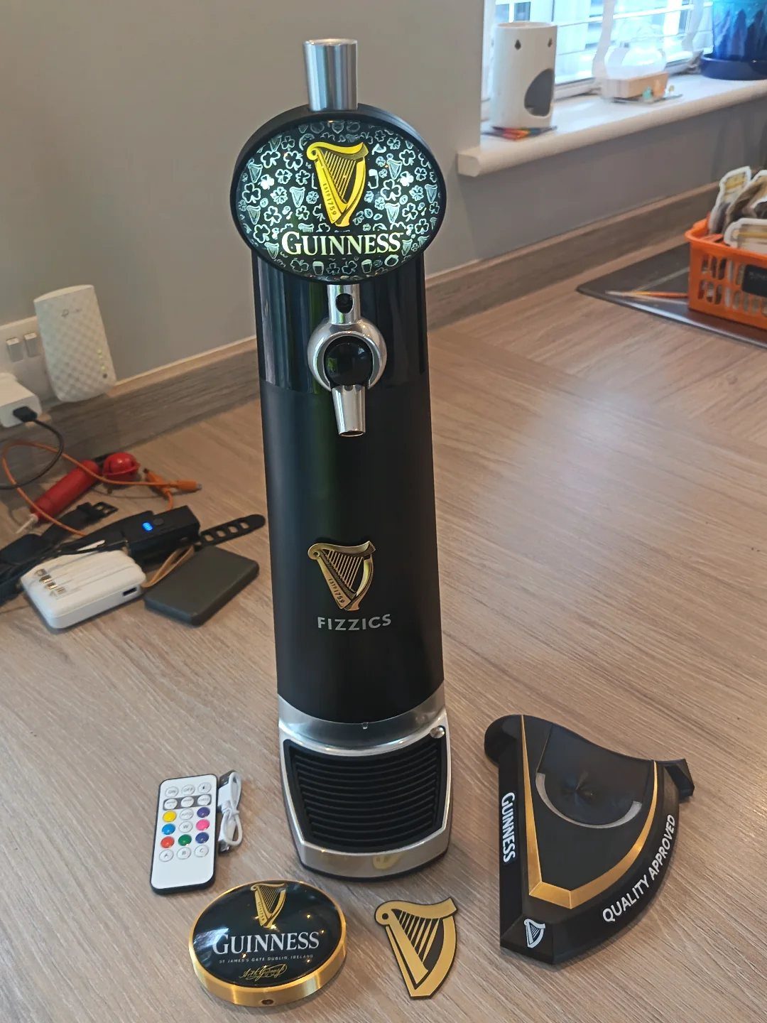 Black FIZZICS beer dispenser with Guinness branding and accessories on a wooden floor.