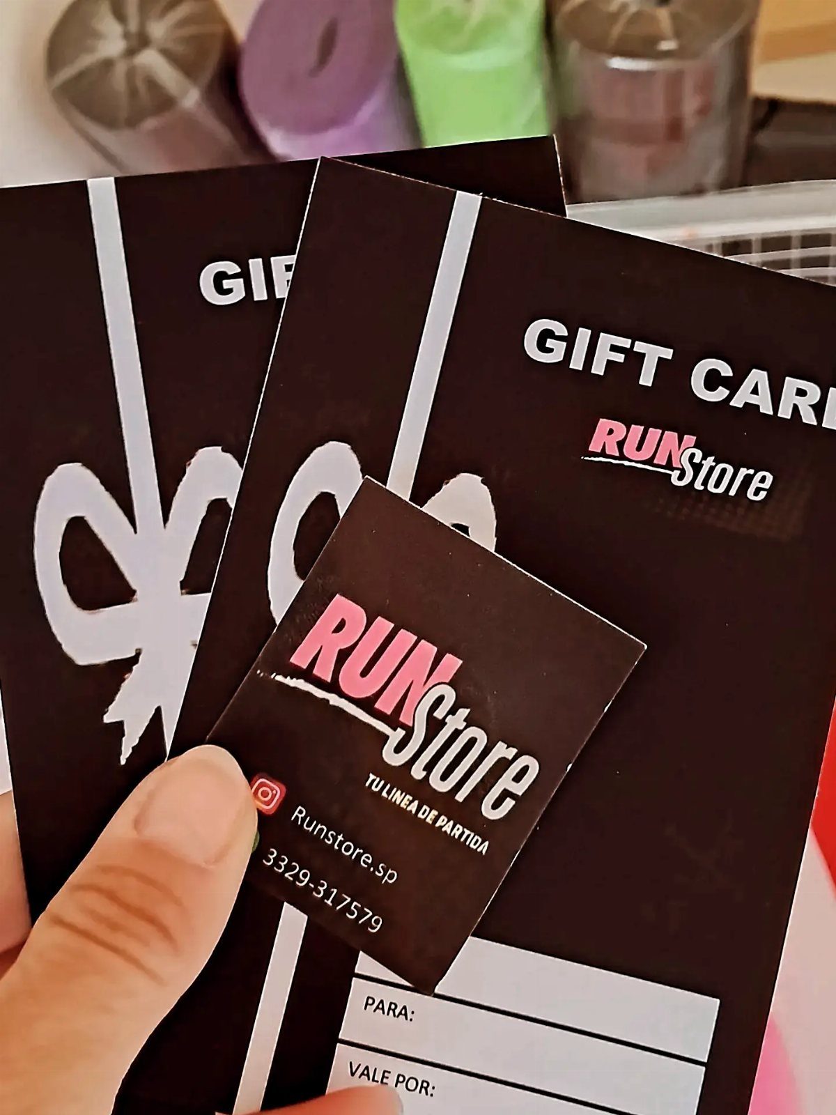 Black gift cards and a business card for a running store held by hand.