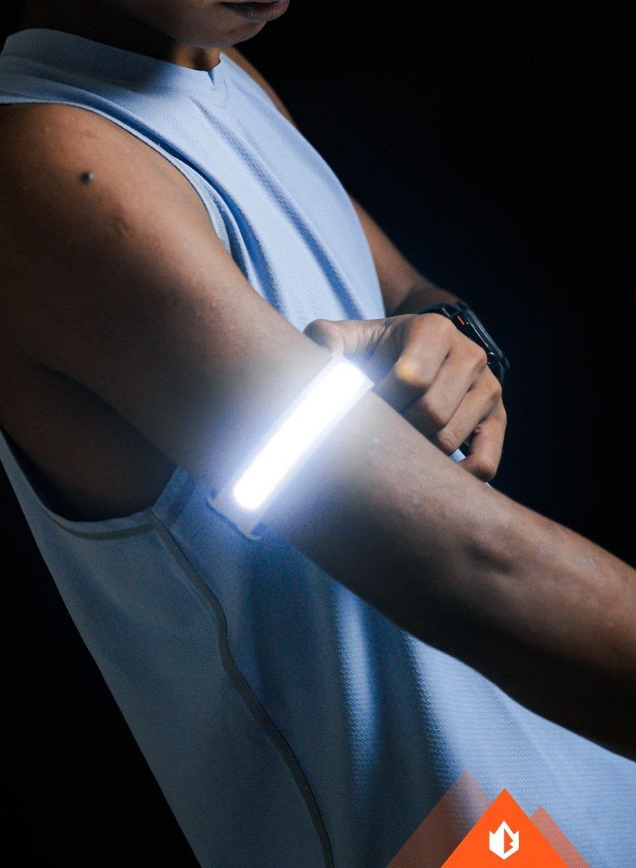 Person wearing a glowing white LED safety arm band for night running.