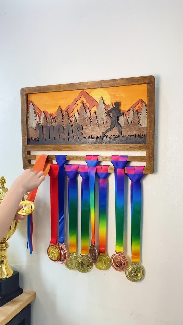 Wooden personalized medal hanger with running silhouette and several colorful race medals.