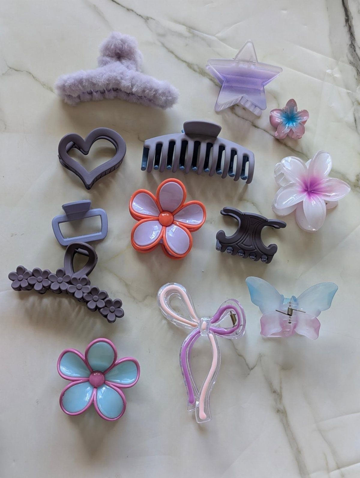 Colorful pastel hair clips and accessories arranged on a white marble background.