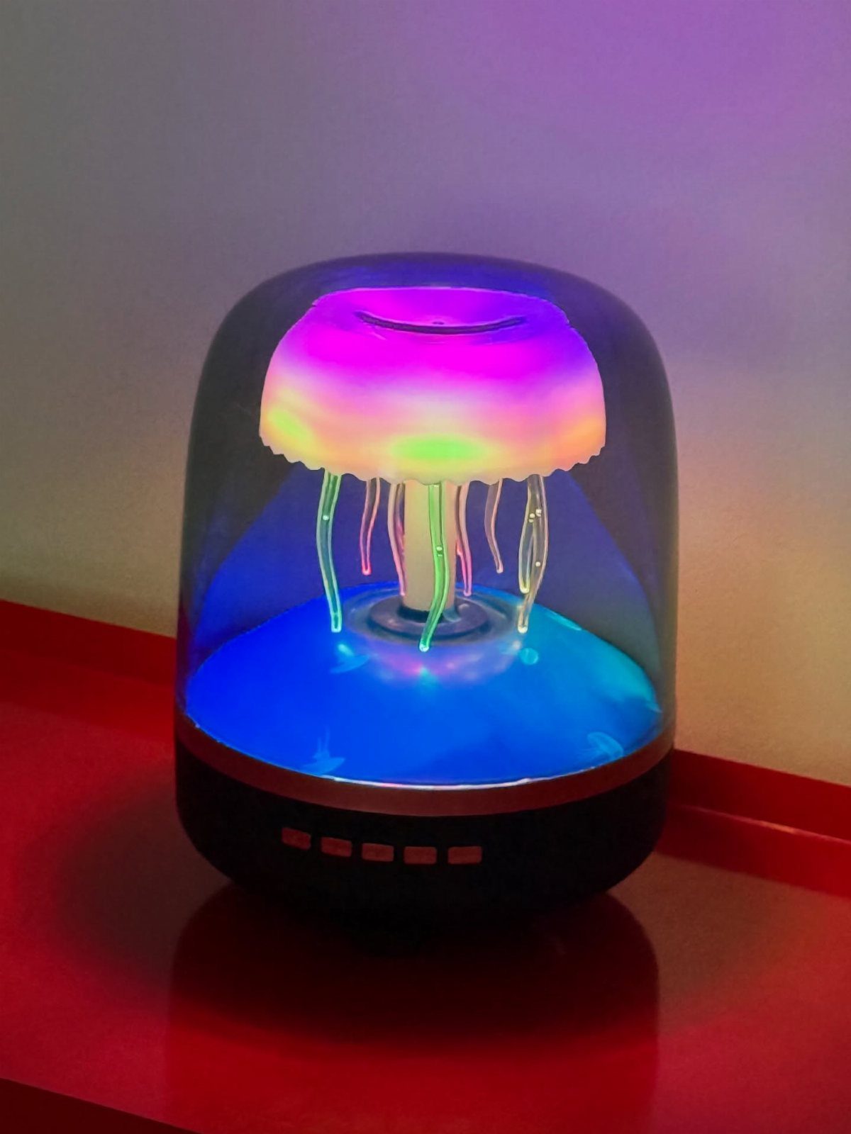 Glowing jellyfish lamp with pink and blue lights on a red surface