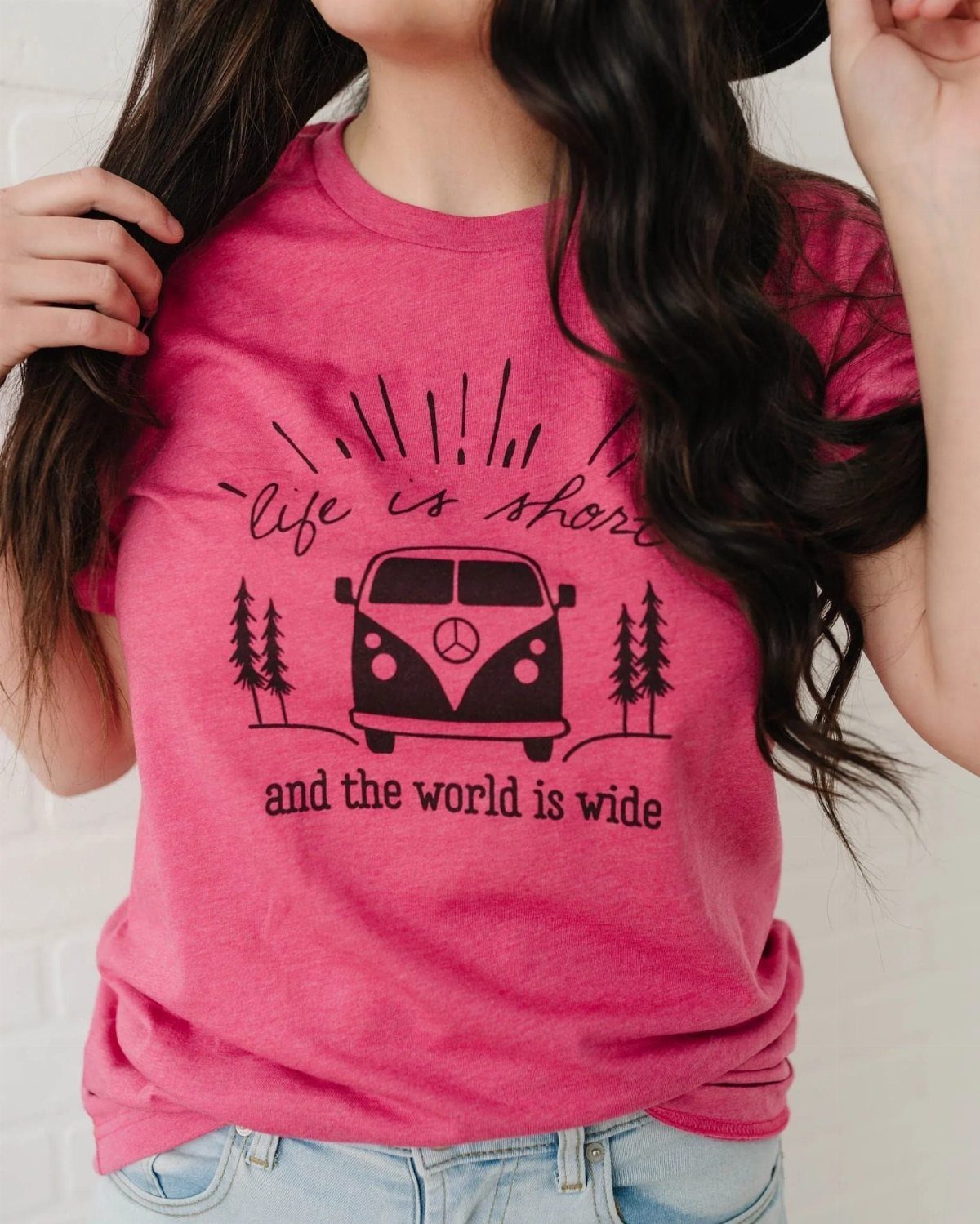 Pink graphic tee featuring a vintage camper van and travel quote on woman