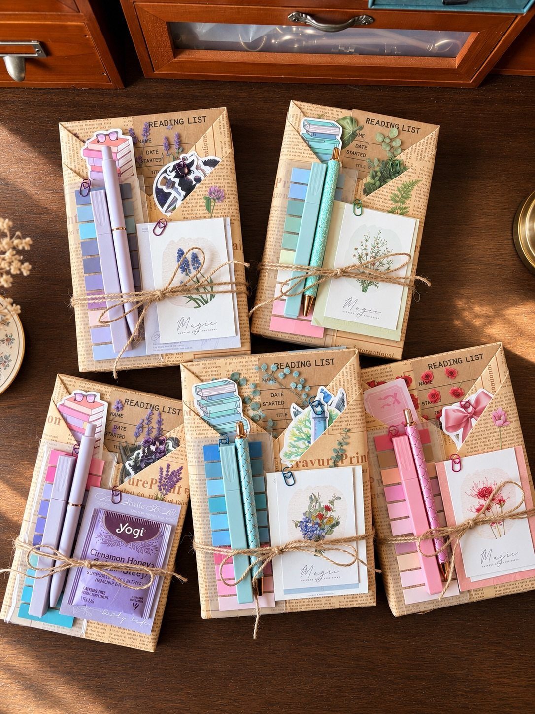 Four pastel stationery sets with notebooks, pens, and stickers tied with twine.