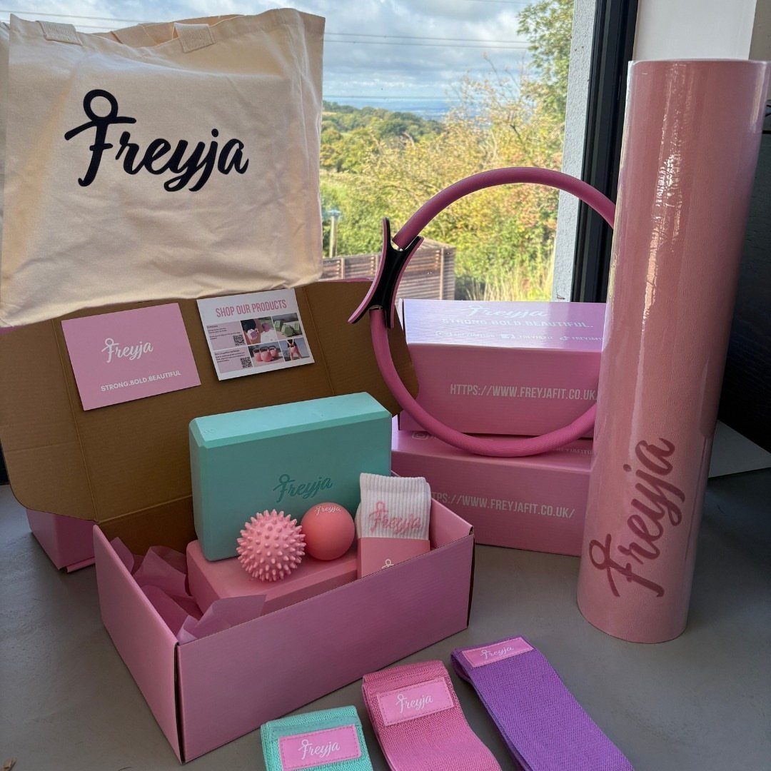 Pink rolled-up yoga mat and fitness accessories in a personalized gift set.