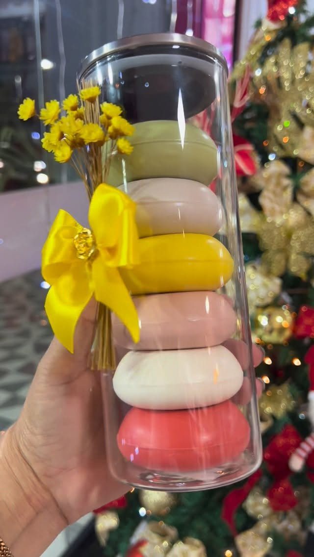 Colorful oval soaps in a clear tube with a yellow ribbon and flowers.