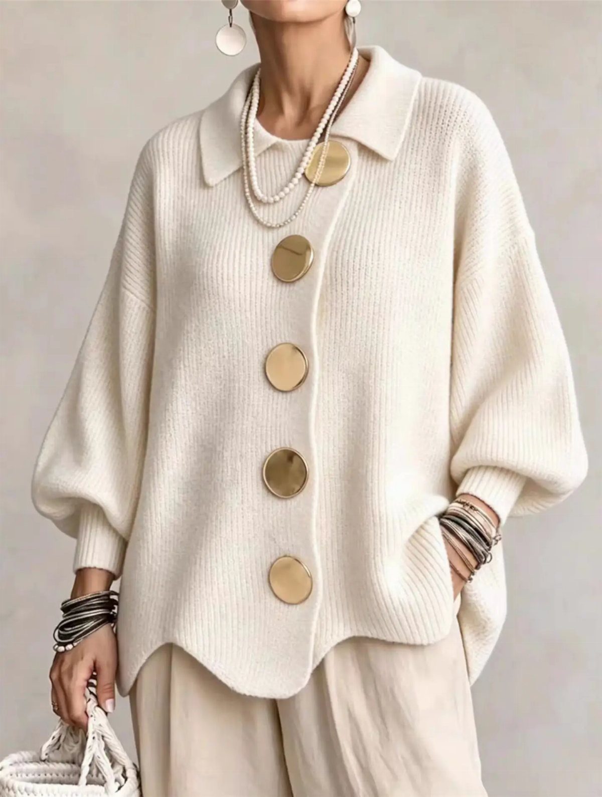 Cream oversized knit cardigan with large gold buttons and pearl necklaces.