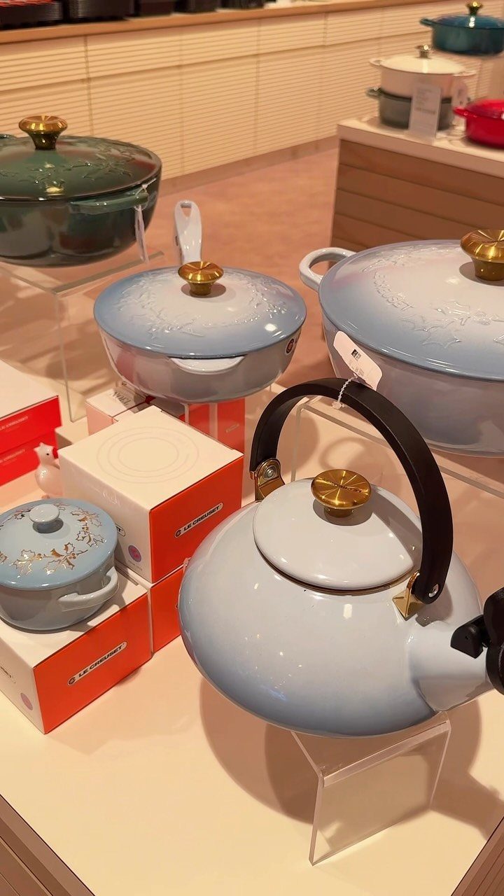 Light blue and green enameled cookware displayed on white store shelves.