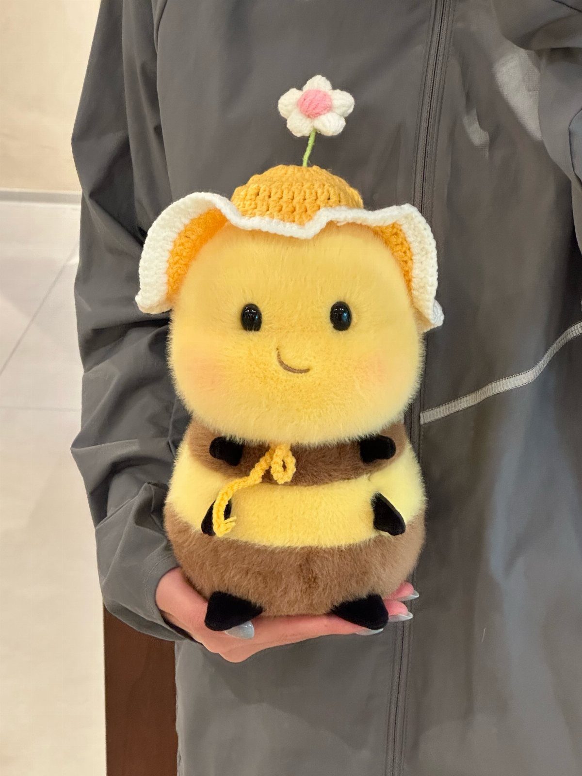 Crocheted plush bee toy with a small flower held by a person