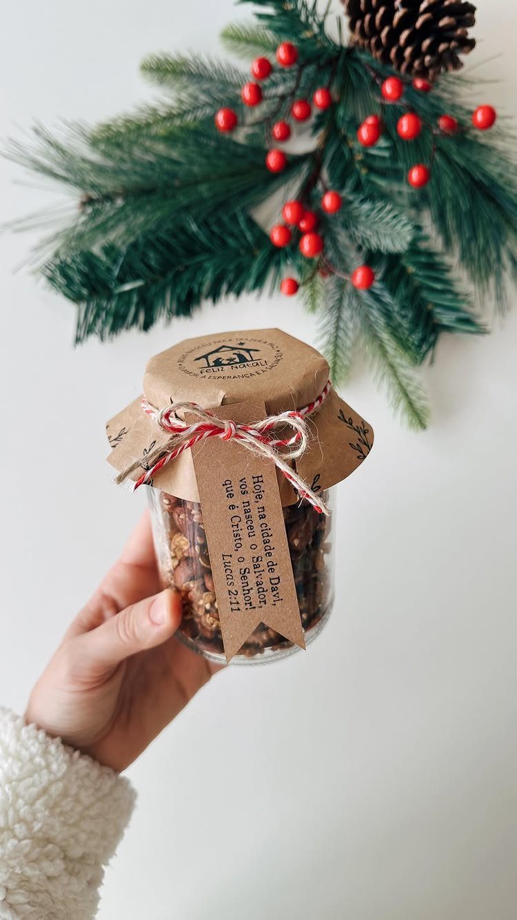 Hand holding a homemade granola jar gift with a festive pine branch background