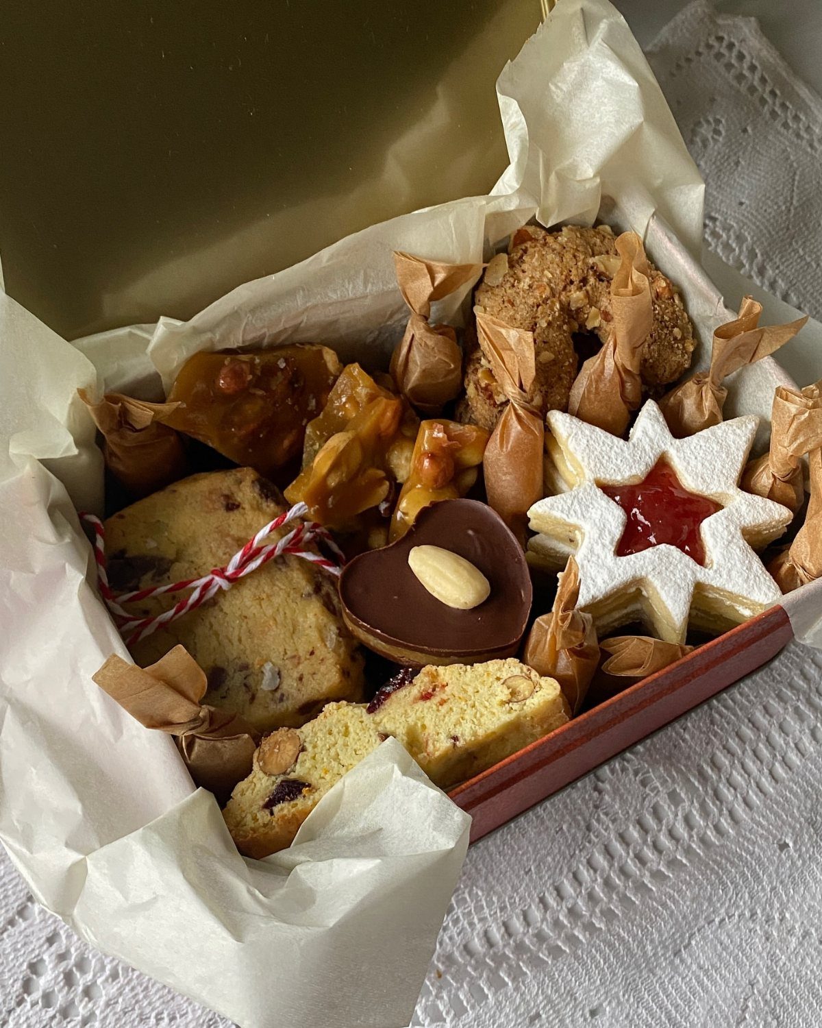 Assorted baked cookies and cakes in a red gift box with parchment paper.