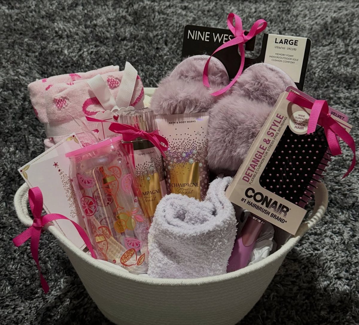 Spa gift basket with purple slippers, towels, and beauty products in a white basket.