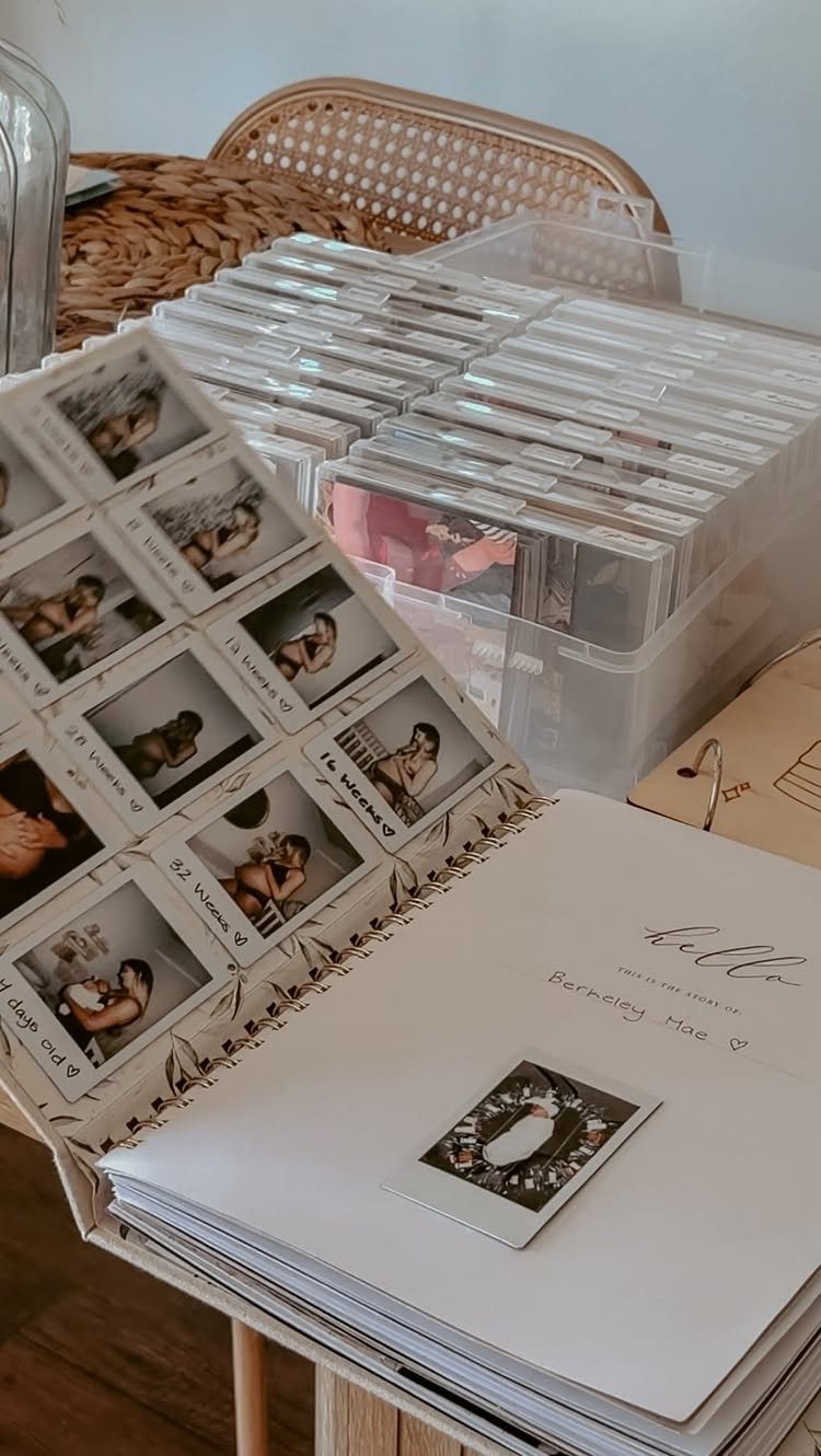 Open baby memory book with milestone photos next to a bin of photo cases.