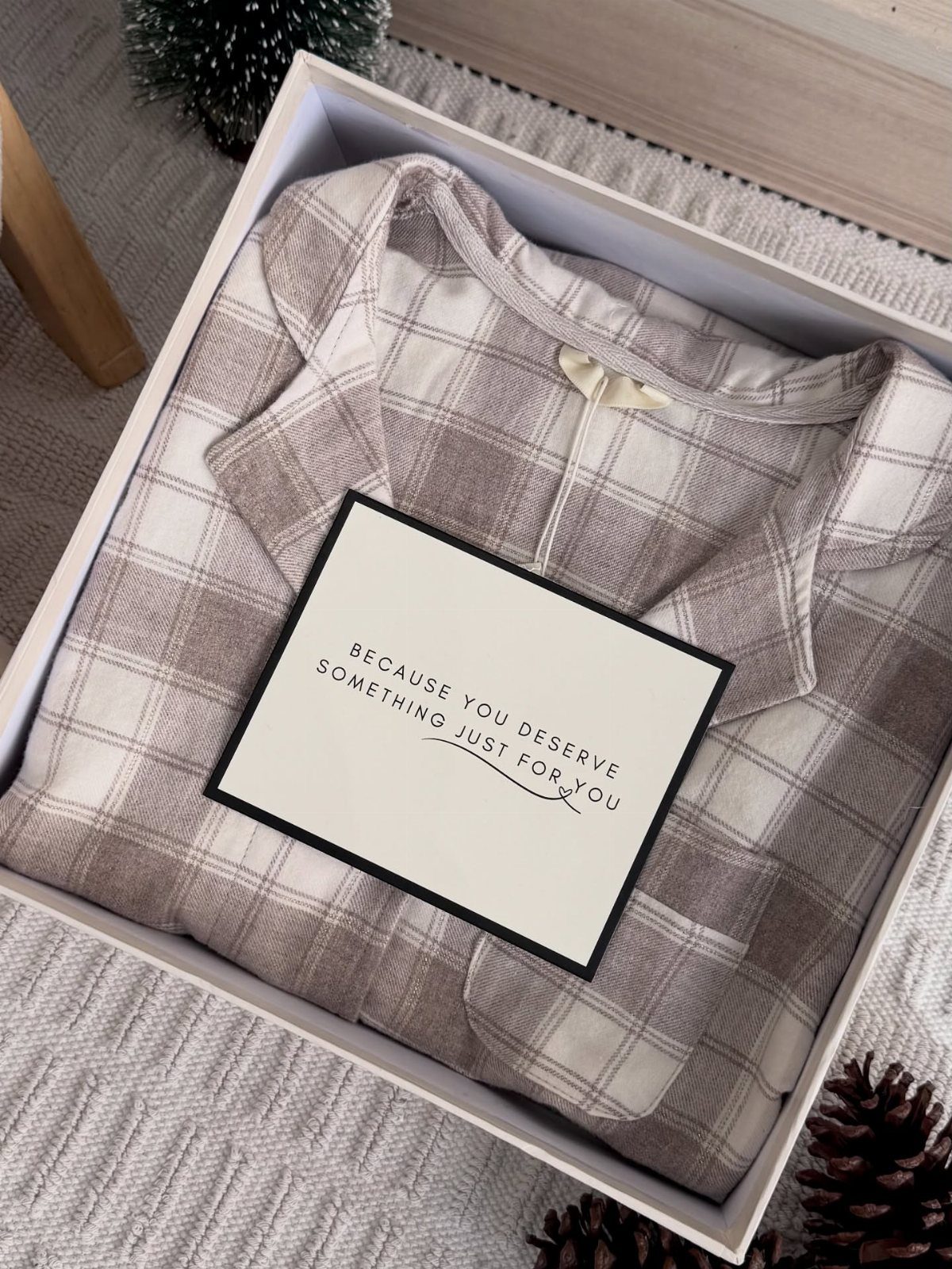 Plaid pajama set and a personalized gift card inside a white gift box.