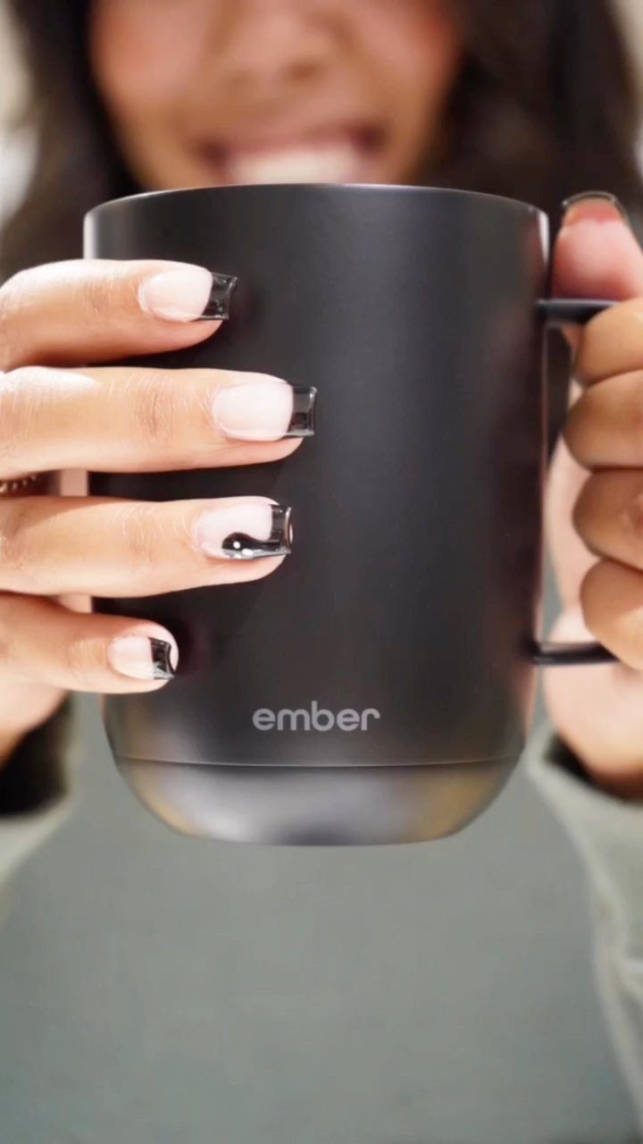 Matte black Ember smart mug held by a person with manicured nails.
