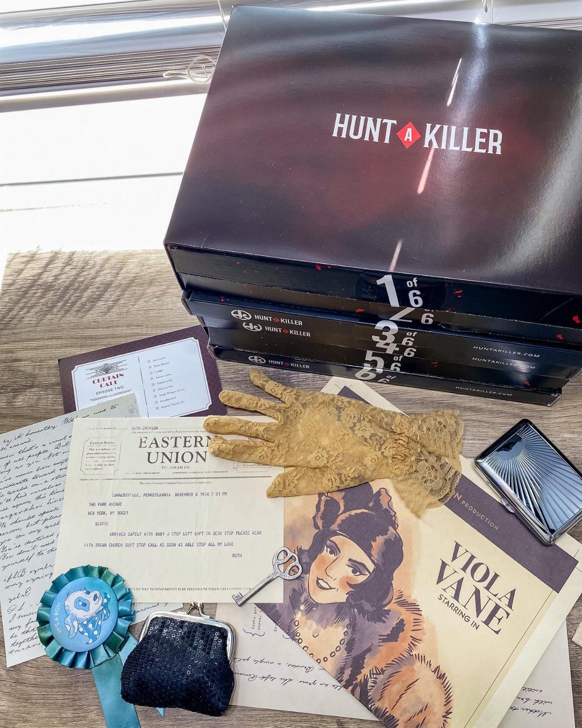 Hunt A Killer mystery boxes with detective clues, a glove, and vintage documents.