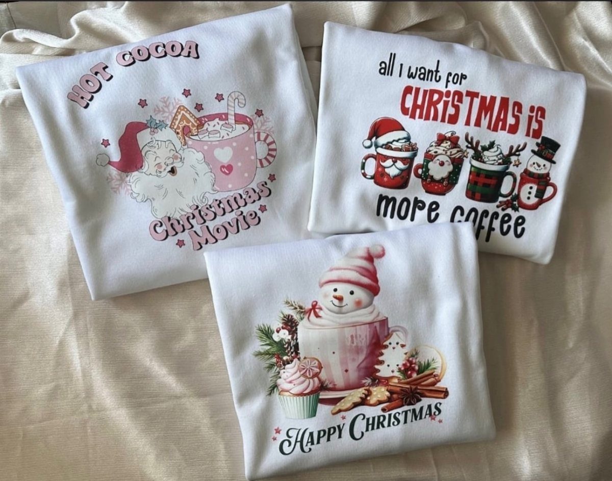Three white Christmas sweatshirts with festive prints and text on cream fabric.