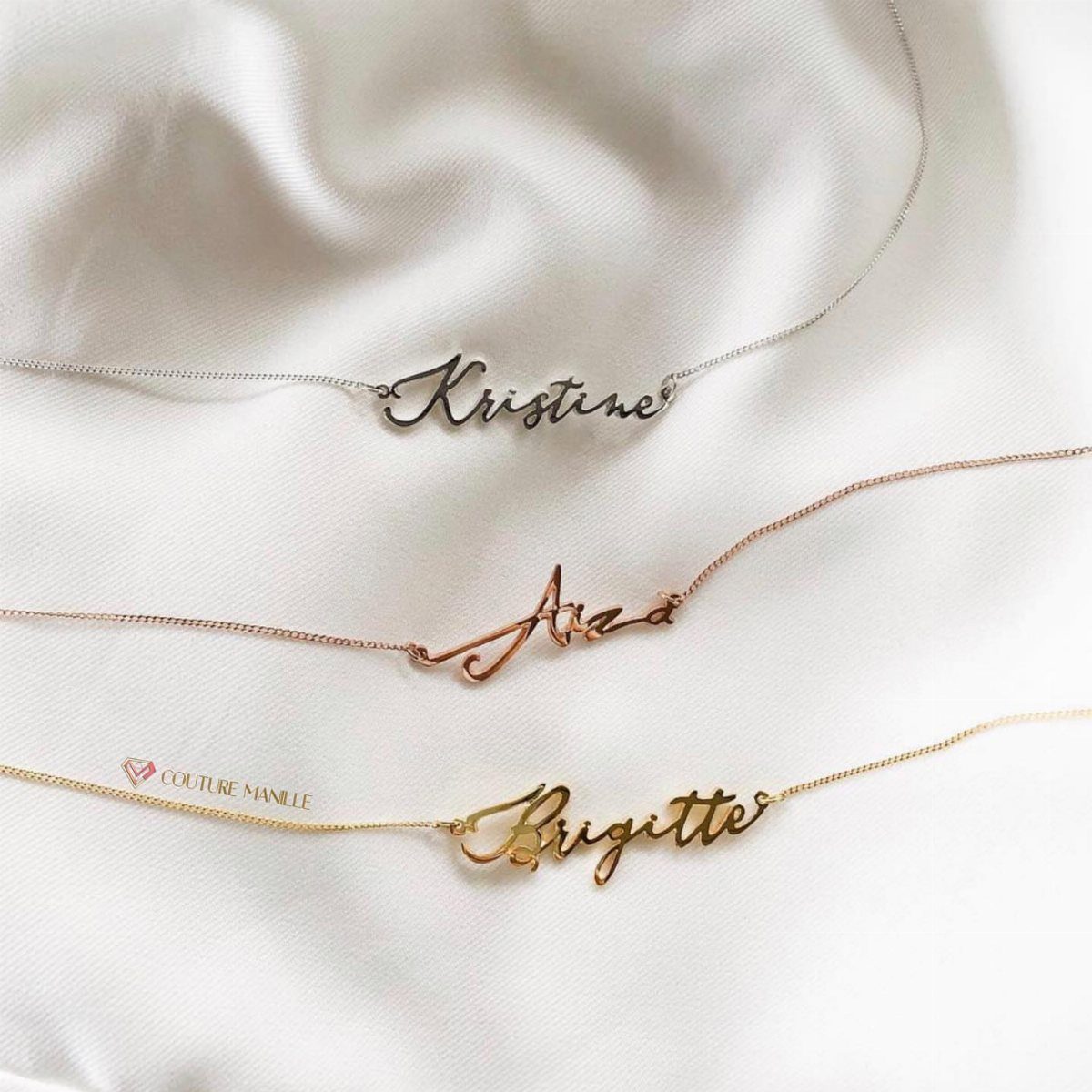 Three customized name necklaces in gold and silver on white satin fabric