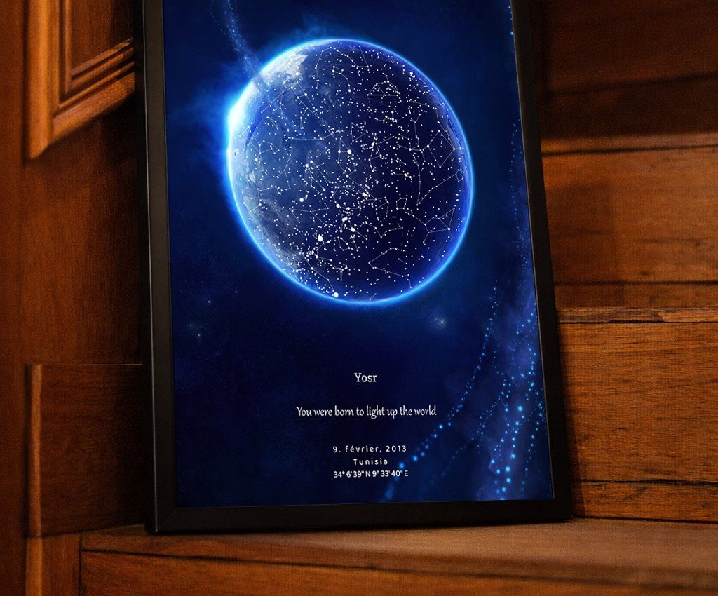 Framed customized star map with a blue celestial sphere resting on wooden stairs.