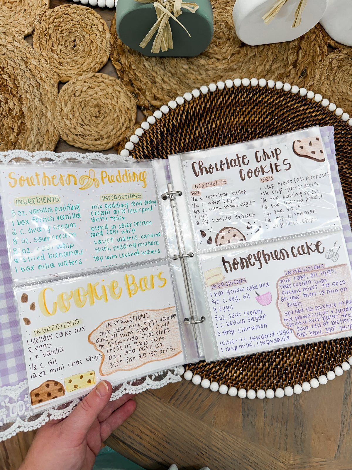 Open binder with handwritten recipe cards for desserts on a woven tray.