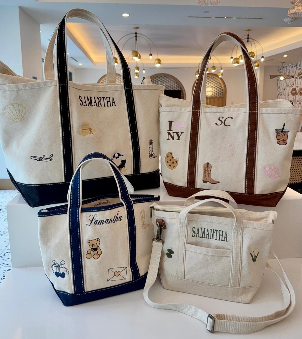 Four personalized cream canvas tote bags with names and small colorful illustrations.