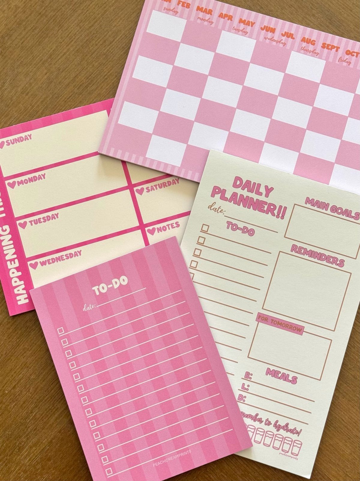 Pink and cream stationery set with planners and to-do lists on wooden table