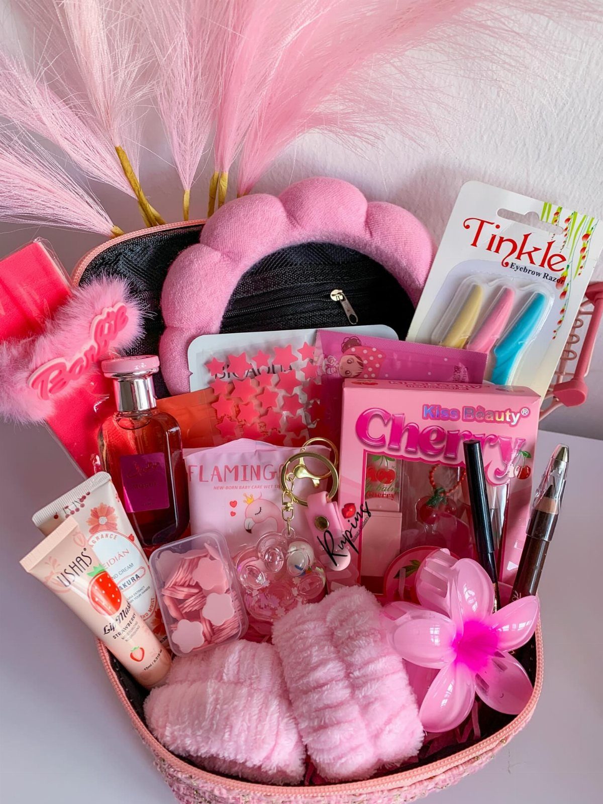 Pink beauty gift basket containing skincare, perfume, and accessories with pink pampas grass.