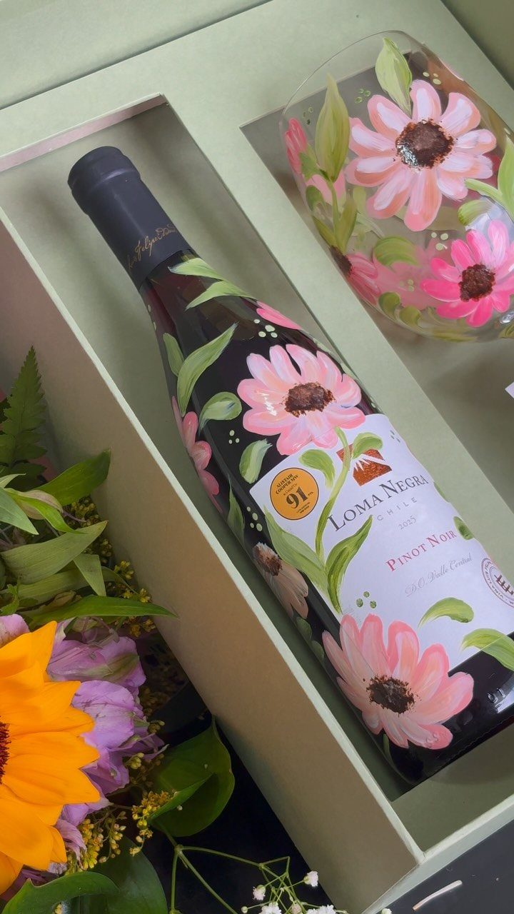 Floral wine bottle and matching glass in a gift box with fresh flowers.