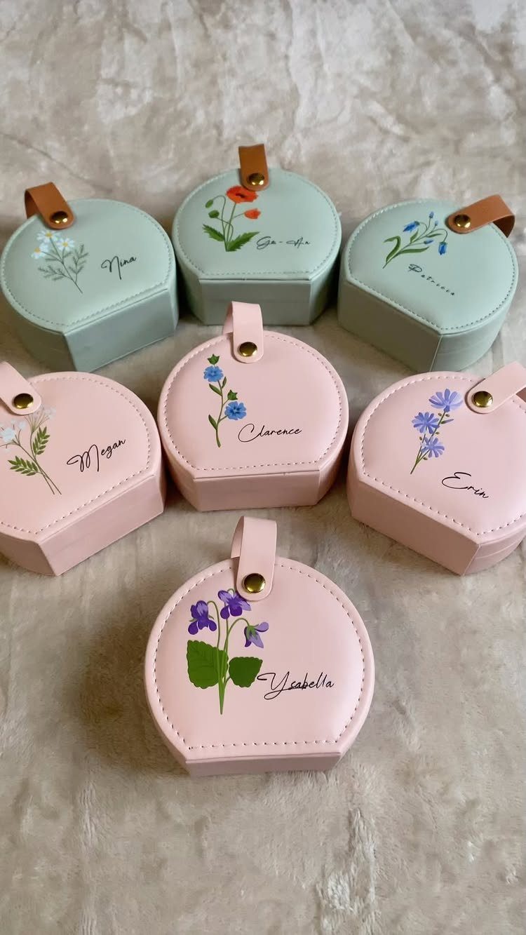 Six personalized hexagonal jewelry travel cases in pink and mint green with floral designs.
