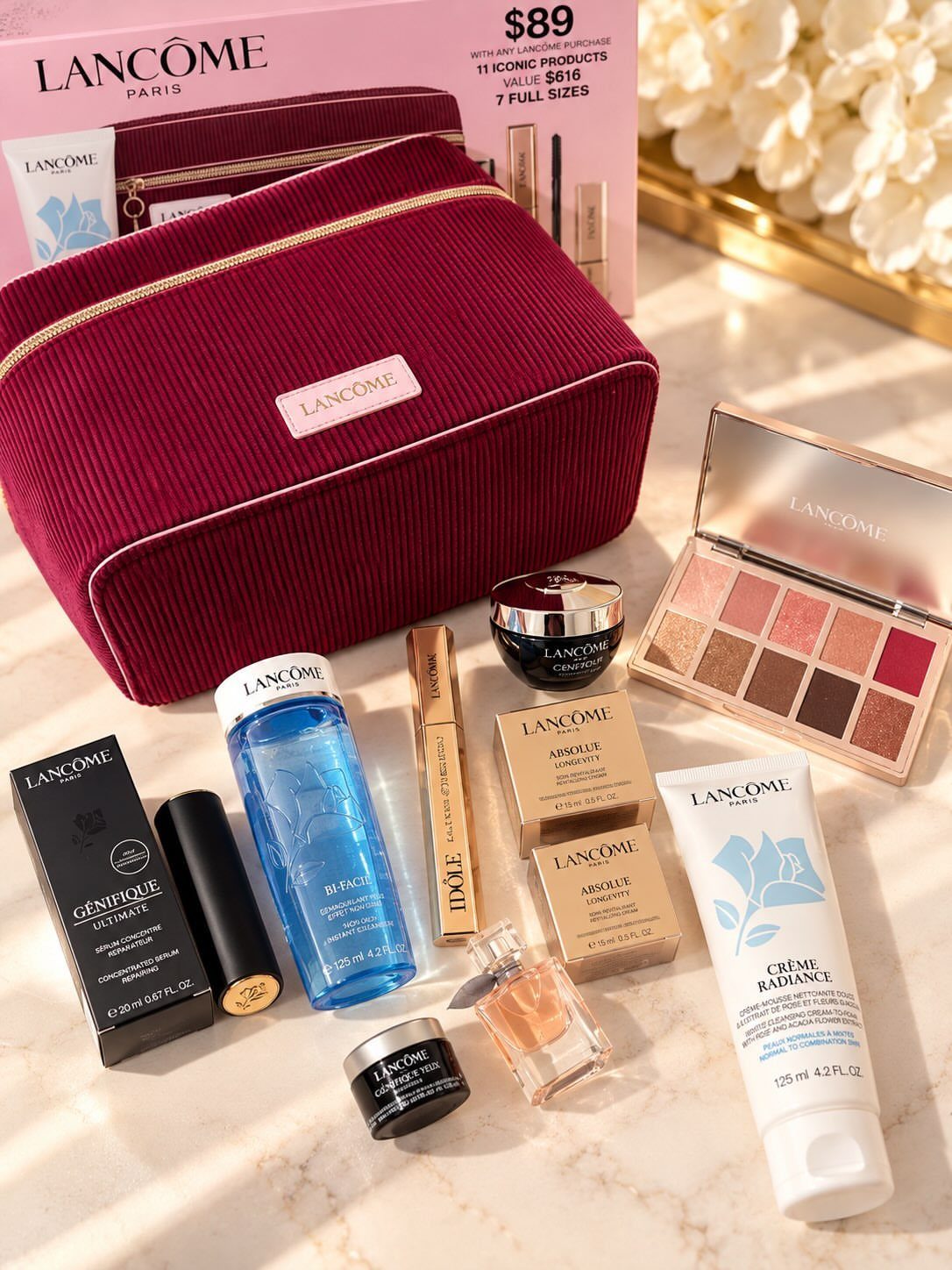 Lancôme beauty gift set with red velvet bag and various skincare products on marble.