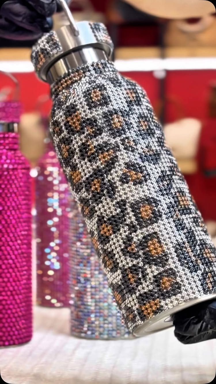 Leopard print rhinestone water bottle held by a hand in a black glove.