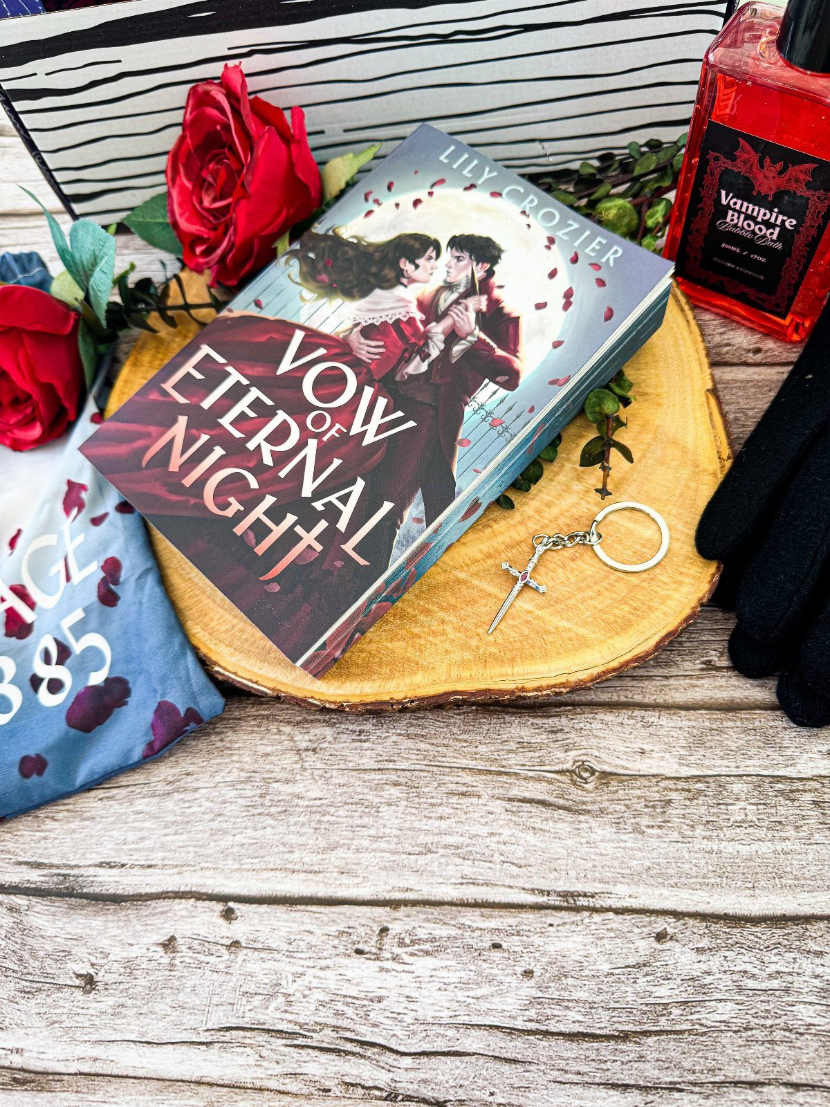 Book titled Vow of Eternal Night with red roses and vampire-themed accessories.