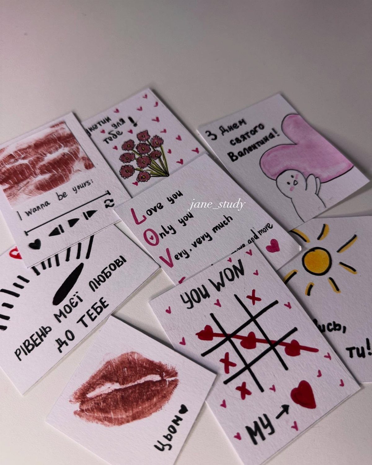 Handmade Valentine cards with red lip prints, hearts, and small drawings on white paper.