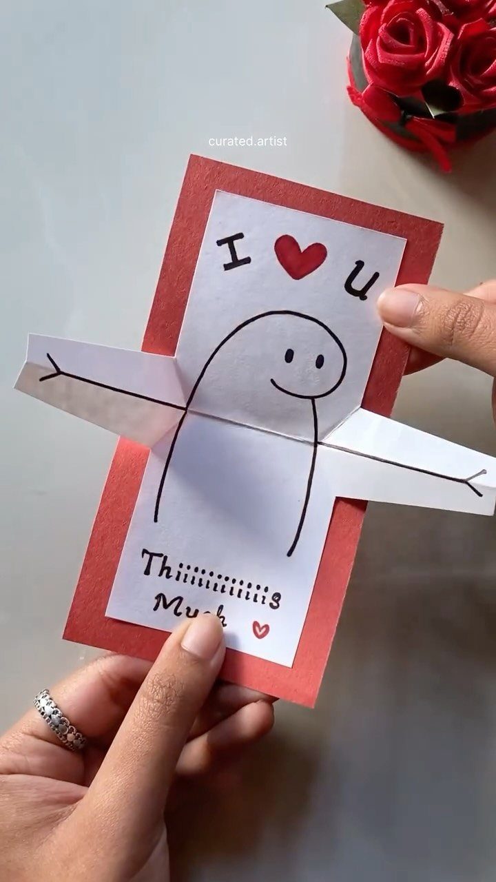 Handmade Valentine's card with a cute character and foldable arms held by hands.