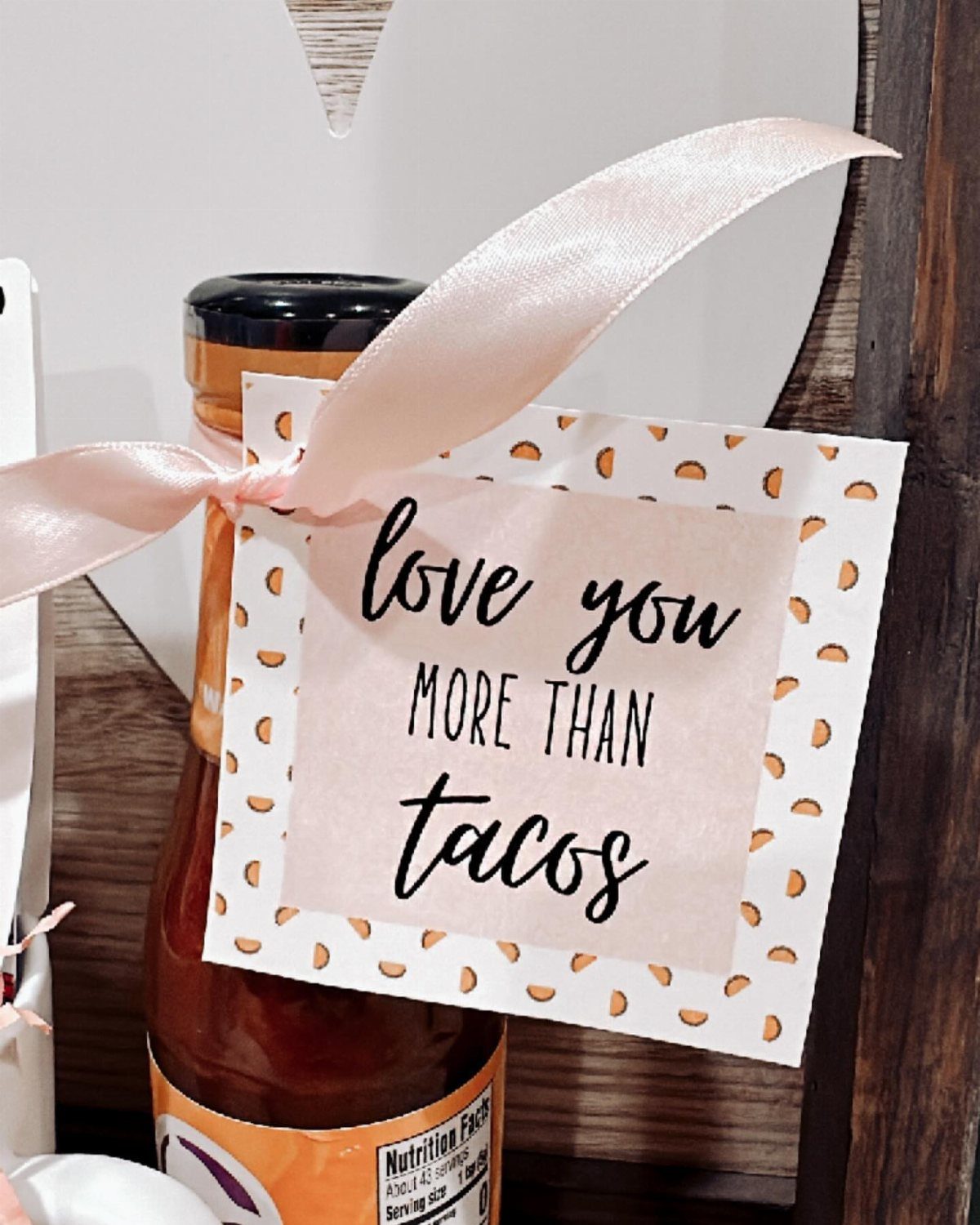 Hot sauce bottle with a pink ribbon and a love you more than tacos card.