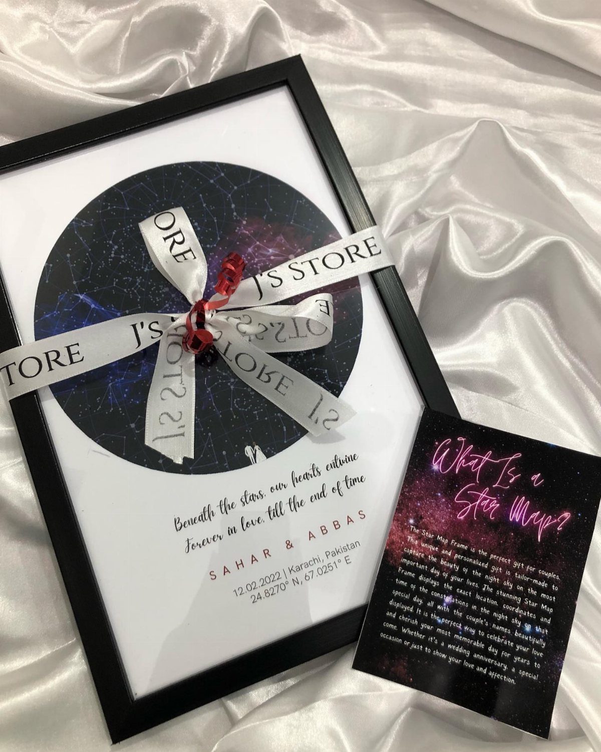 Personalized star map in a black frame with a white ribbon on satin fabric.