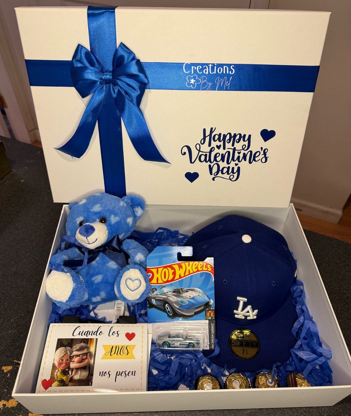 White Valentine's gift box filled with blue themed items and a couple's photo.