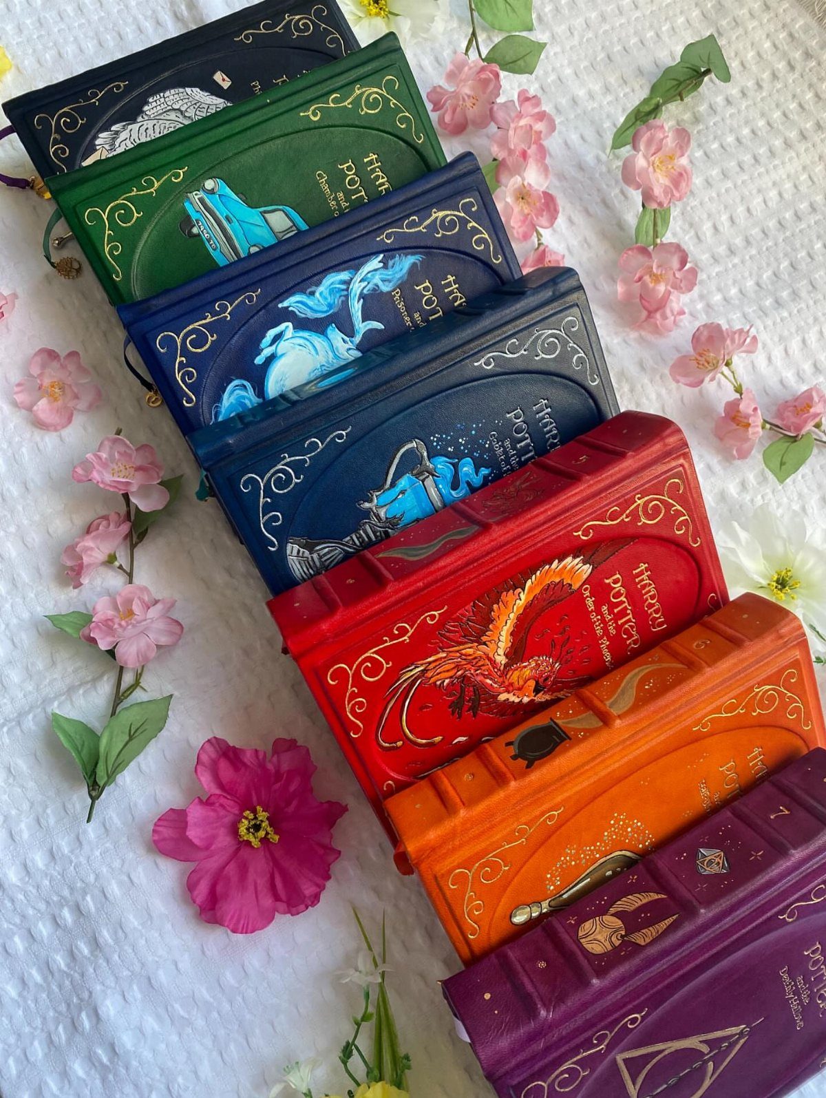 25 Best Harry Potter Gifts for Every Wizarding Fan in 2026 13 Colorful Harry Potter illustrated hardcover books arranged with pink flowers on white fabric.