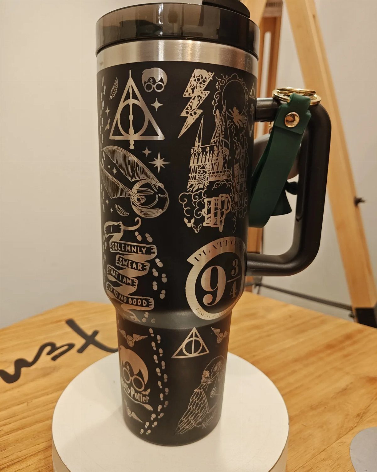 25 Best Harry Potter Gifts for Every Wizarding Fan in 2026 14 Black insulated travel tumbler with gold Harry Potter engravings on a wooden table