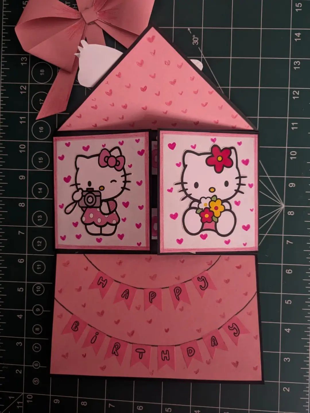 Handmade pink Hello Kitty birthday card open on a green cutting mat.