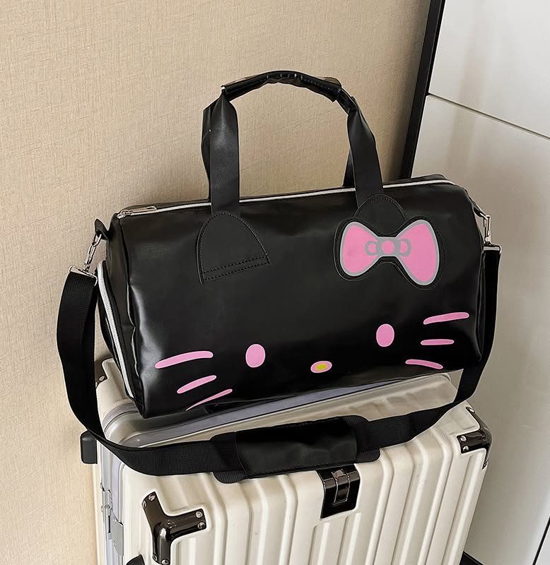 Black Hello Kitty duffel bag resting on a white hard-shell suitcase.