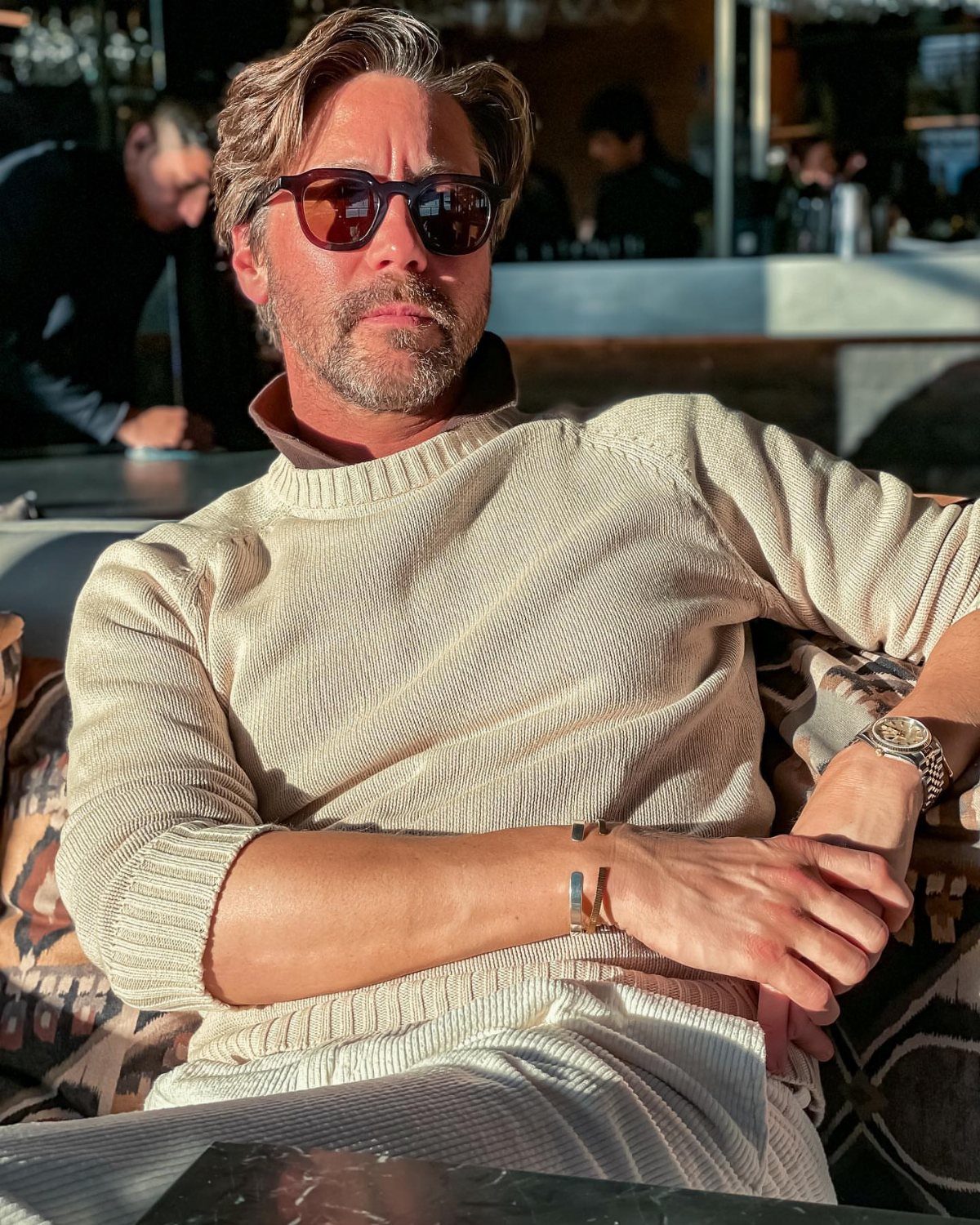 Man wearing a cream ribbed cashmere crewneck sweater and matching trousers outdoors.