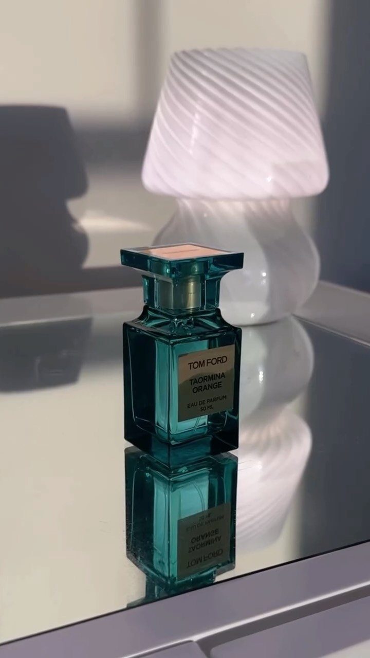 Tom Ford fragrance bottle on a reflective surface with a white lamp background