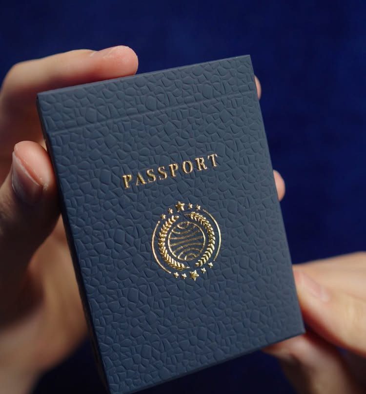 Dark blue leather passport cover with gold foil lettering held by two hands.