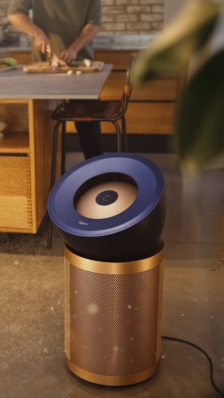 Modern navy and gold speaker standing on a concrete floor in a kitchen.