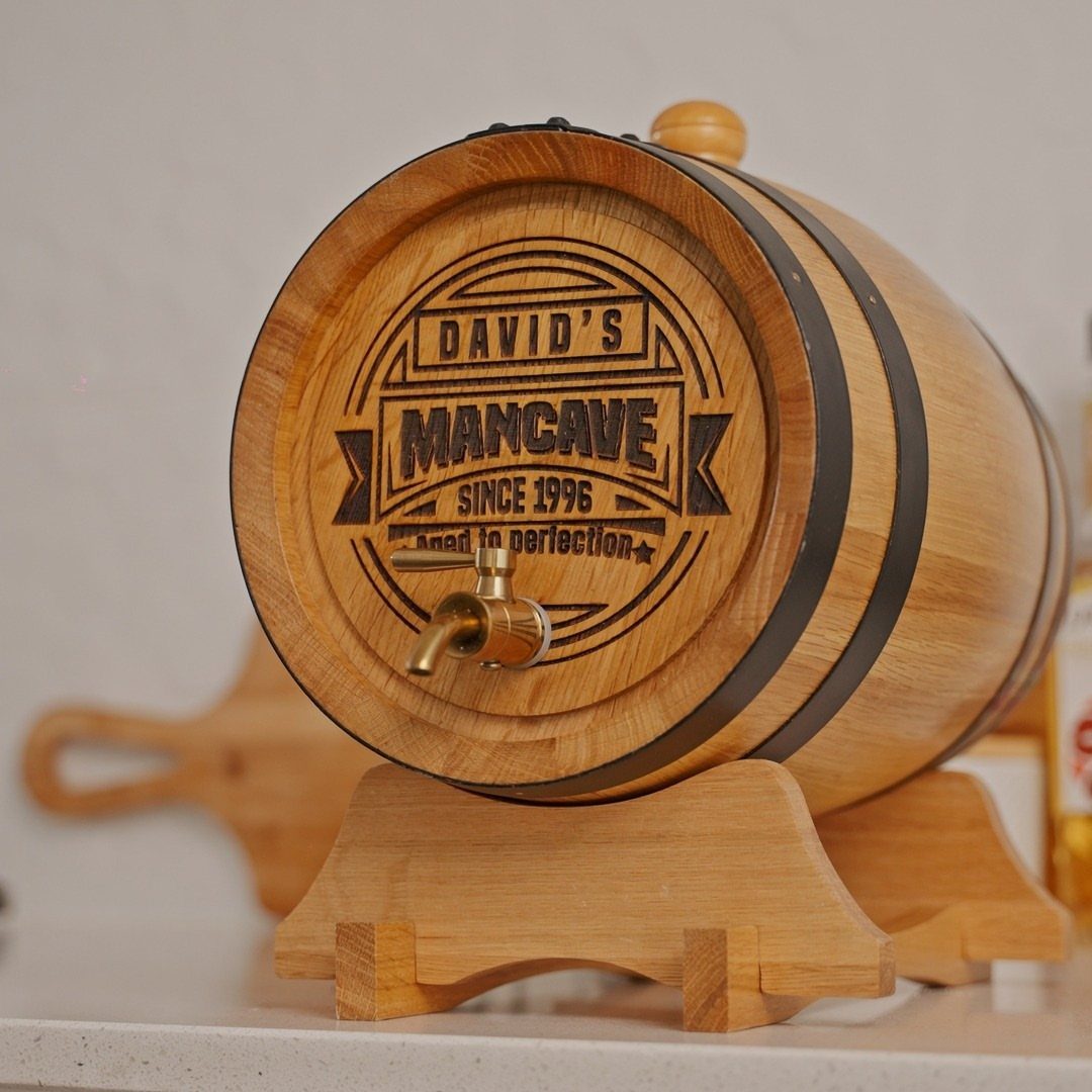 Personalized wooden whiskey barrel on a stand with engraved text and brass spigot.