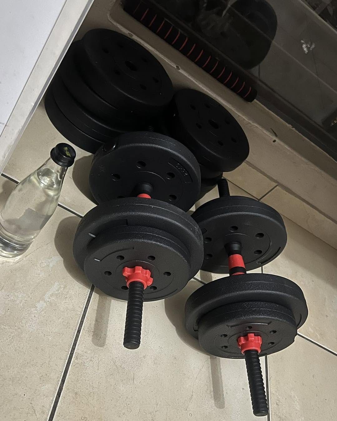 20 Ideal Boyfriend Gifts He'll Actually Use and Keep 16 Adjustable black dumbbells and weight plates on a tiled floor with a water bottle.